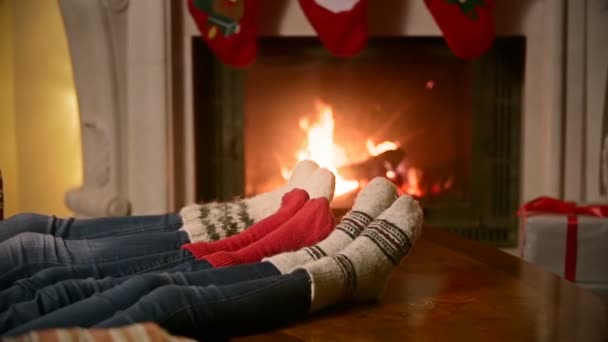 Familia con niño en calcetines de lana de punto calentamiento en la chimenea en casa — Vídeo de stock