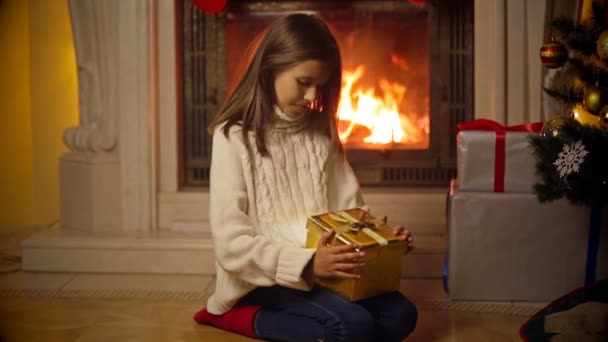 Cute girl in sweater opening magical Christmas gift box. Light and sparkles flying out of the box — Stock Video
