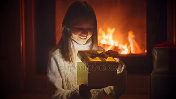 Portrait of excited girl looking inside of Christmas gift box. Magic dust and glowing lights flying out of open box — Stock Video