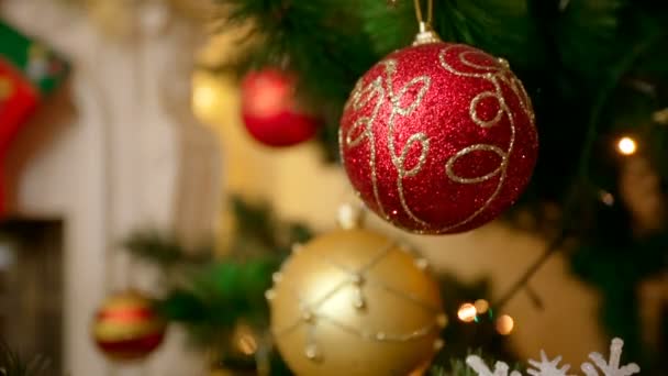 Κινηματογράφηση σε πρώτο πλάνο από χρυσά και κόκκινα στολίδια κρέμονται από το χριστουγεννιάτικο δέντρο στο σαλόνι — Αρχείο Βίντεο