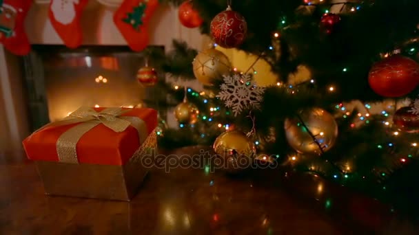 Dolly záběr vánoční dárek v červeném rámečku se zlatou mašlí v obývacím pokoji s hořící krb