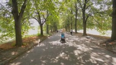 Mutlu genç anne bebek oğlu sarılma ve ile gezinmek Park'ta yürüyüş