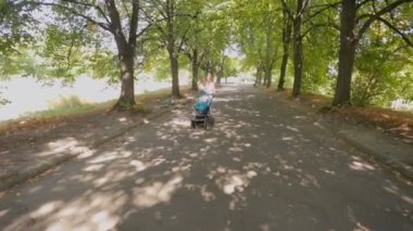 Mutlu genç anne bebek evlat ve çocuk arabası yaz Park'ta yürüyüş Steadicam atış