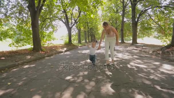 Adorable bébé garçon tenant la main de la mère et marchant au parc — Video