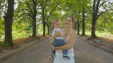 Steadicam atış bir bebek oğlu sarılma ve Park'ta yürüyüş güzel genç anne