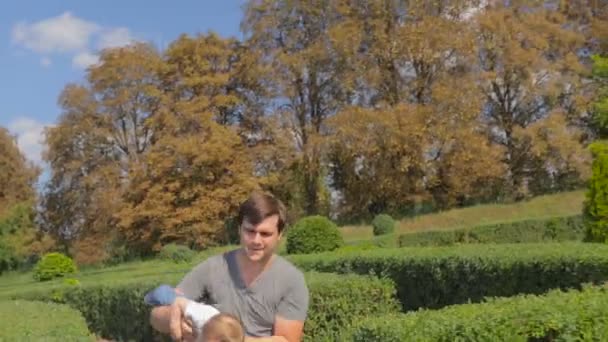 Gelukkig jonge vader knuffelen en spelen met zijn zoontje in het park — Stockvideo