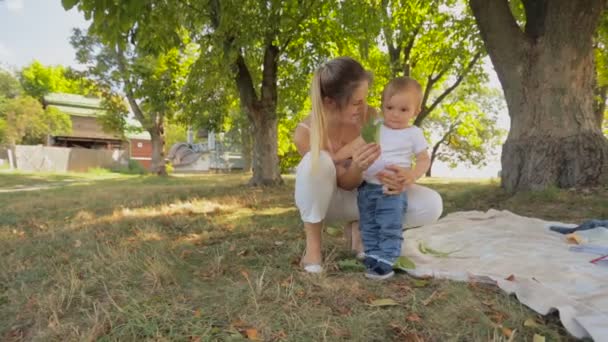 mignon tout-petit garçon avec belle jeune mère sous l'arbre au parc 