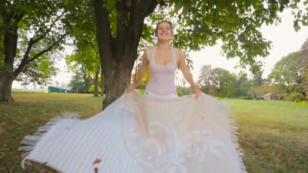 Belle jeune femme se préparant pour le pique-nique et assis sur la couverture sous l'arbre 