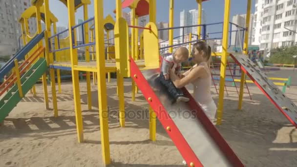 Niedlicher kleiner Junge spielt mit junger Mutter auf dem Spielplatz — Stockvideo