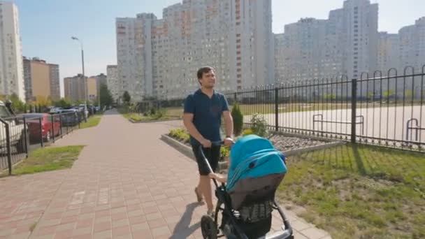 Feliz jovem pai andando com carrinho de bebê na rua — Vídeo de Stock