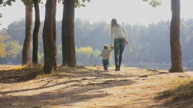 Annesi elini tutarak ve orman yürüyüş 1 yaşında yürümeye başlayan çocuk