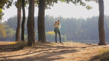 Mutlu gülümseyen anne bebek oğlu tutan ve orman göle bakarak