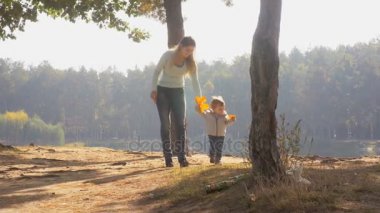 genç anne bebek oğlu sonbahar orman ile yürüyüş 4 k görüntüleri