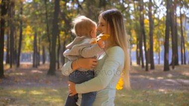 Şirin bebek çocuk anne ve holding sonbahar yaprakları sarılma ağır çekim görüntüleri