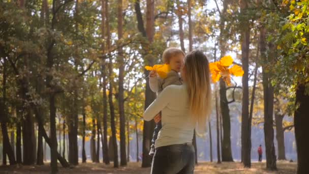 Slow motion porträtt av glad ung mor med baby son på hösten park — Stockvideo