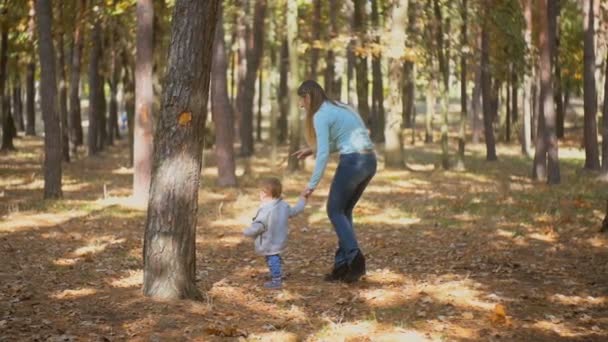 Imágenes en cámara lenta del lindo bebé sosteniendo a las madres de la mano y caminando en el parque — Vídeos de Stock