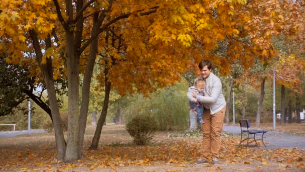Glückliches Baby mit jungem Vater beim Spielen und Spazierengehen im Herbstpark — Stockvideo