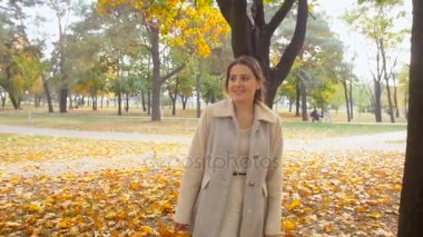 Sonbahar Park'ta yürüyüş paltolu güzel genç kadın ağır çekim görüntüleri