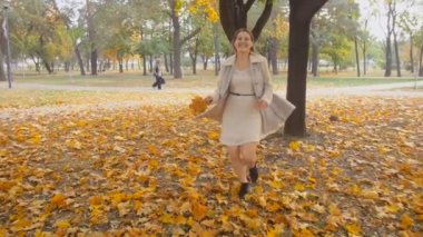 Ağır çekim görüntüleri ile çalışan güzel gülen kadının elinde sonbahar park adlı yaprakları