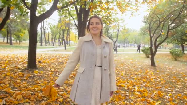 Images au ralenti de belle femme romantique tenant des feuilles jaunes et marchant au parc d'automne — Video