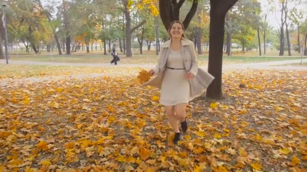 Slow motion záběry krásné rozesmáté ženy s listy v ruce na podzimní park