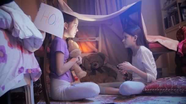 Duas adolescentes de pijama sentadas no chão no quarto e contando histórias assustadoras com lanterna — Vídeo de Stock