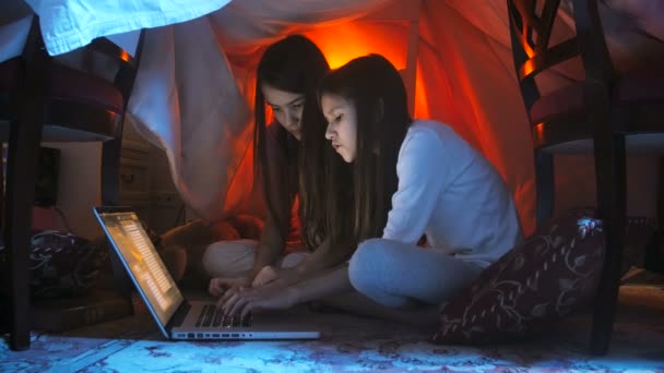 Filmagem 4k de duas meninas adolescentes usando laptop à noite no chão no quarto — Vídeo de Stock