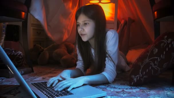 4k dolly shot de fille adolescente tapant message dans les médias sociaux sur ordinateur portable la nuit — Video