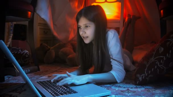 十几岁的女孩在晚上在地板上使用笔记本电脑的 4 k 镜头。 — 图库视频影像