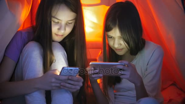 4 k βίντεο των δύο έφηβων κοριτσιών χρησιμοποιώντας smartphones στην κρεβατοκάμαρα πριν πάτε για ύπνο — Αρχείο Βίντεο