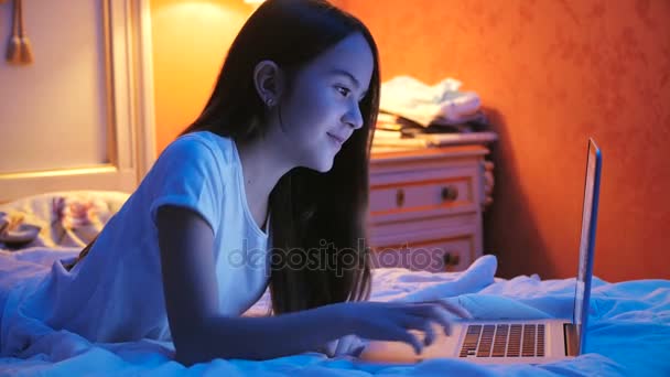 Retrato de menina bonita fazendo videochamada via laptop na cama à noite — Vídeo de Stock