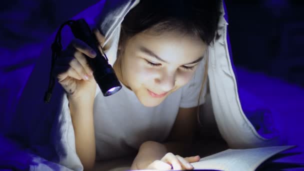 Linda chica acostada en la cama libro de lectura con linterna en la noche — Vídeo de stock