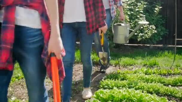 Close up 4k video of family carrying gardening tools walking at backyard garden — стоковое видео