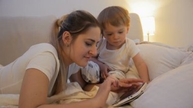 Anne yatakta dijital tablet kullanarak bakarak şirin yürümeye başlayan çocuk