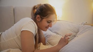 yatakta yatan ve Web sitesinde dijital tablet kaydırma güzel gülümseyen kadın 4 k görüntüleri