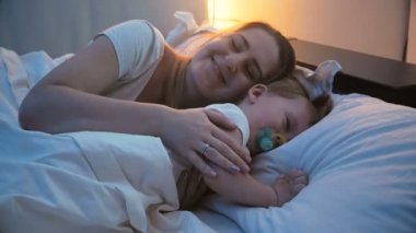 genç anne yatakta yürümeye başlayan çocuk oğlu koymak için çalışırken 4 k görüntüleri