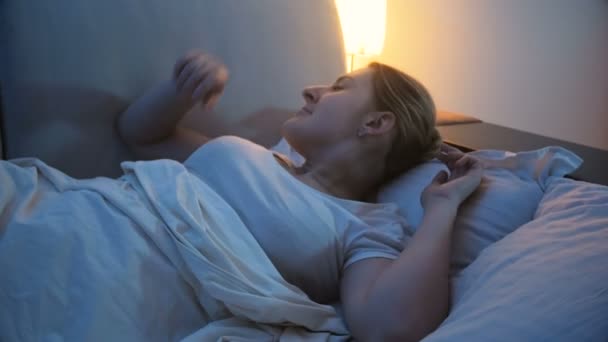 Imágenes de 4k de una mujer joven apagando la luz en el dormitorio antes de irse a dormir — Vídeos de Stock