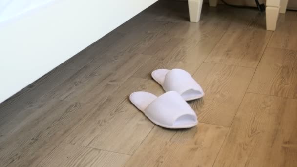 4 k video van jonge vrouwelijke voeten dragen van pantoffels naast bed in hotelkamer — Stockvideo