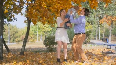 Sarılma ve bebek oğulları ile sonbahar parkta oynarken mutlu anne ağır çekim görüntüleri