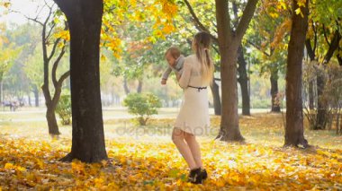 Güzel genç anne bebek evlat sonbahar park holding ağır çekim görüntüleri