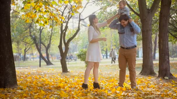 Schattige babyjongen op vaders schouders zitten en genieten van tijd met familie hebben in het park — Stockvideo
