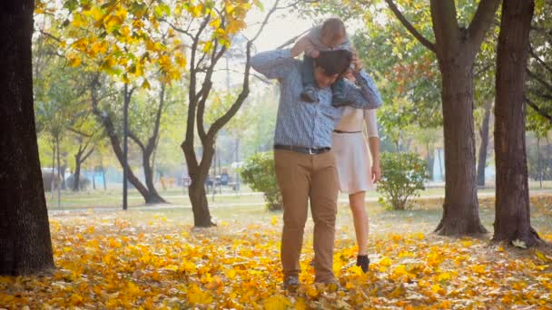 Mutlu anne ve babanın bebeklerini ile sonbahar parkta oynarken ağır çekim görüntüleri — Stok video