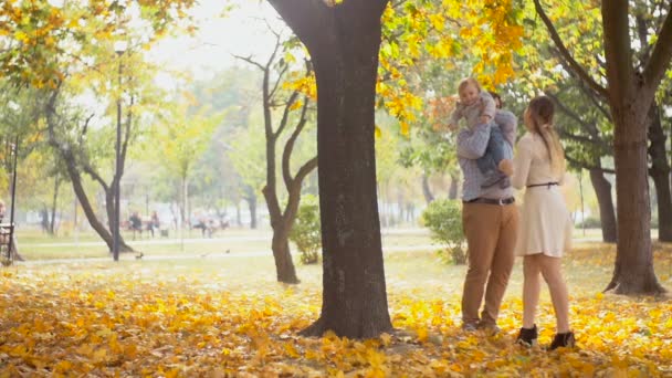 快乐年轻的母亲和父亲拥抱襁褓中的儿子在秋天公园的慢动作镜头 — 图库视频影像
