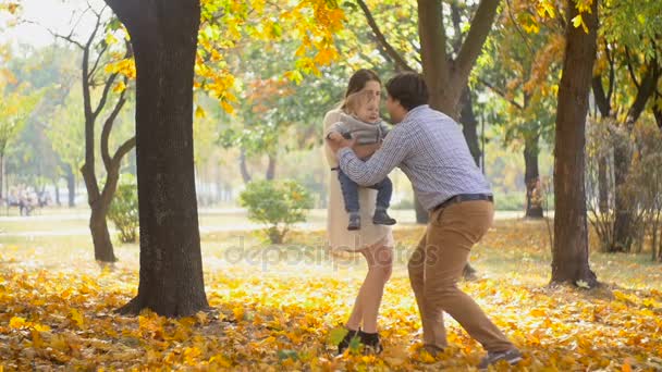 Медленная съемка счастливого отца, бегущего к своему маленькому сыну и растущего в воздухе в осеннем парке — стоковое видео