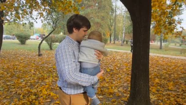 Images au ralenti du jeune père aimant câlinant son fils bébé au parc 