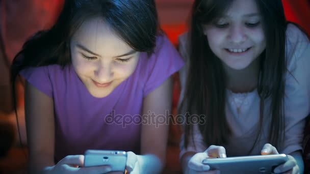 Imágenes de 4k de dos hermanas jugando en teléfonos móviles antes de irse a dormir — Vídeo de stock