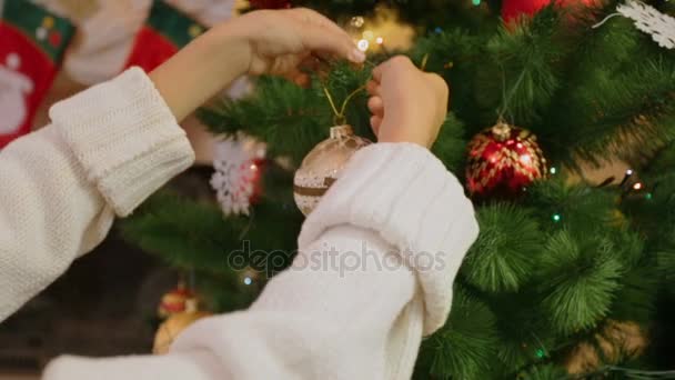 Primer plano de niña decorando el árbol de Navidad. Cámara se acerca de las manos a bauble — Vídeo de stock