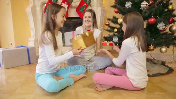 Família feliz sentados na árvore de Natal e dando presente uns aos outros — Vídeo de Stock