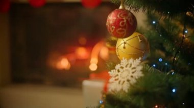 Noel ağacı üzerinde altın ve kırmızı baubles closeup görüntüsü. Arka planda yanan şömine.