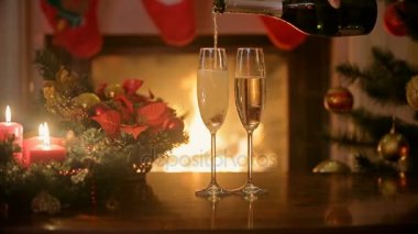 Noel akşam yemeği masada iki kadeh şampanya dökme. Arka plan, yanan şömine